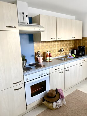 A modern kitchen with light wood cabinets, a stainless steel sink, and a coffee maker.