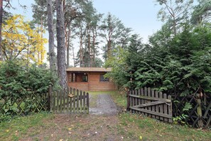 A wooden cabin with a brick pathway leading to it, surrounded by dense forest. - Apartment 'Waldblick' with Private Terrace, Private Garden and Wi-Fi (Berlin)