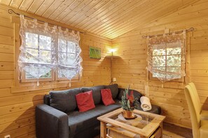Ein Holzblockhaus-Innenraum mit einer Couch, einem Tisch und einem Stuhl.