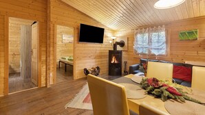 A wooden interior with a fireplace, a flat-screen TV, and a sofa. - Apartment 'Waldblick' with Private Terrace, Private Garden and Wi-Fi (Berlin)