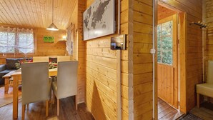 A wooden interior with a dining table, chairs, a map on the wall, and a door leading outside. - Apartment 'Waldblick' with Private Terrace, Private Garden and Wi-Fi (Berlin)