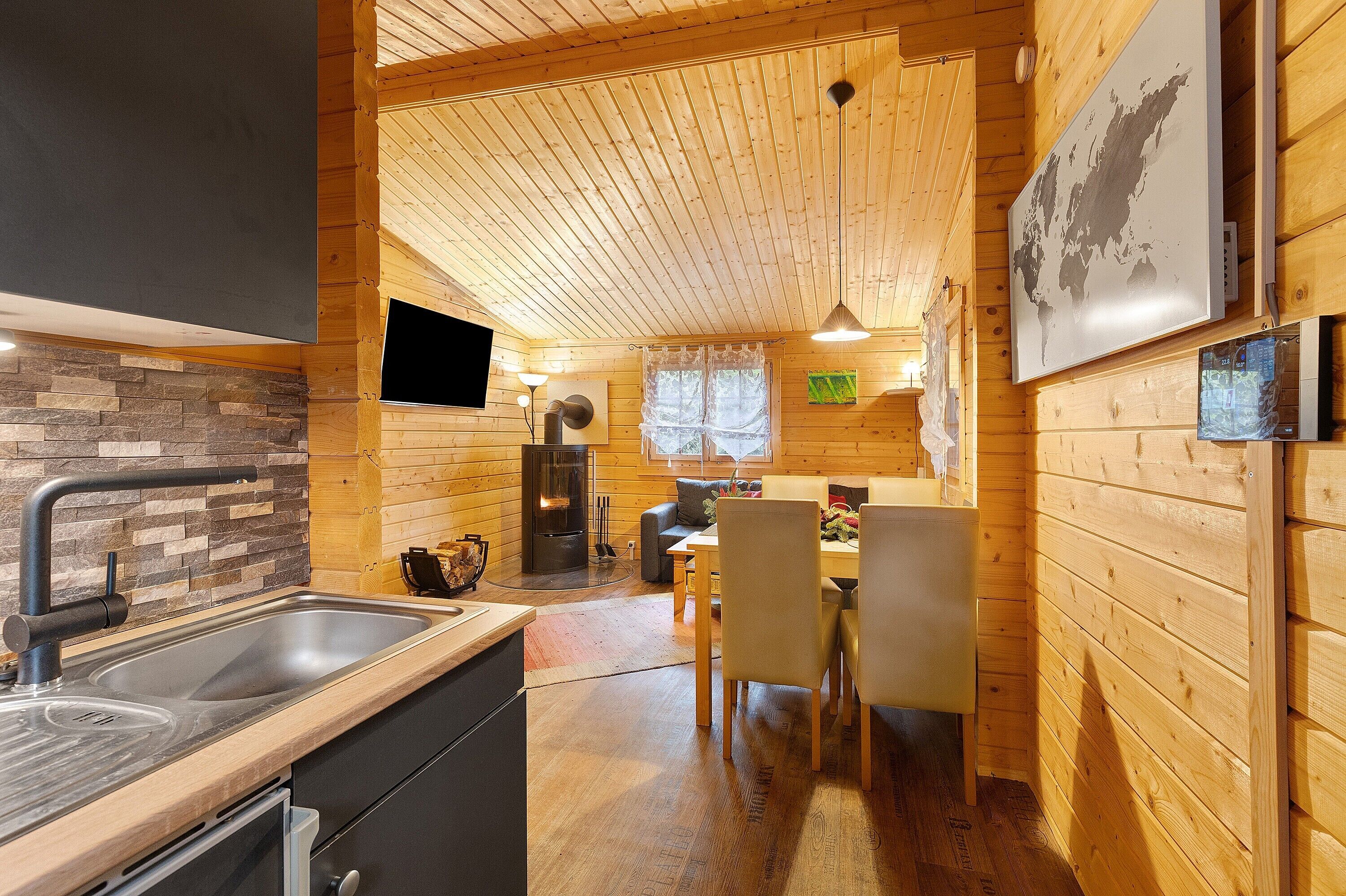 A wooden interior with a kitchen, dining area, and a fireplace.