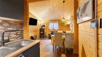 A wooden interior with a kitchen, dining area, and a fireplace.
