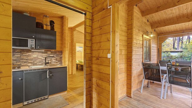 A wooden cabin interior with a kitchen area featuring a microwave, cabinets, and a sink. - Apartment 'Waldblick' with Private Terrace, Private Garden and Wi-Fi (Berlin)