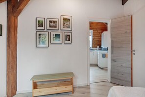 Um quarto com um banco de madeira, uma cama e uma parede com quadros.