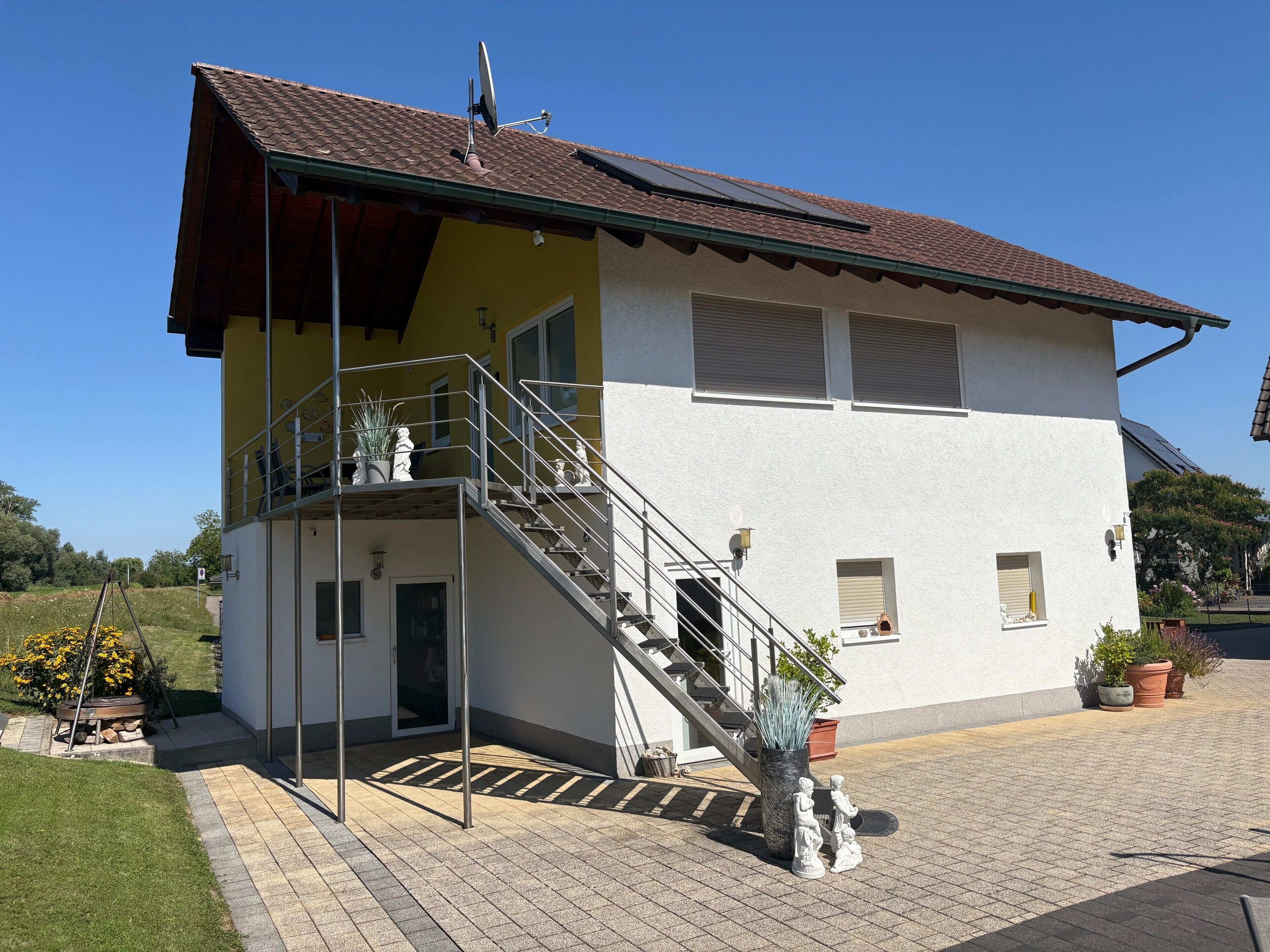 A two-story house with a balcony, a staircase, and a paved driveway.