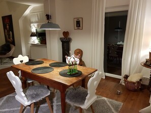 A dining area with a wooden table, white chairs, and a vase with flowers.