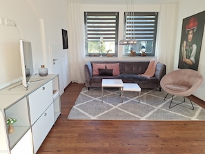 A modern living room with a sofa, a coffee table, a TV, and a decorative chair.