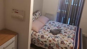 Ein Schlafzimmer mit einem Bett, einem Schminktisch und einem Fenster mit Vorhängen.