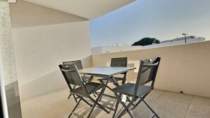 Ein Balkon mit Tisch und vier Stühlen.