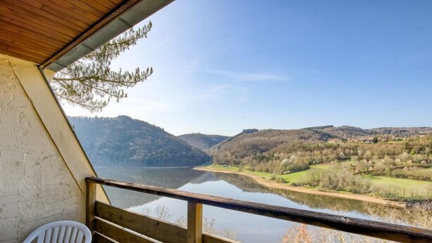 A balcony with a wooden railing overlooking a lake and hills. - Appartement au Calme! Balcon avec Vue + Piscine (Miremont)