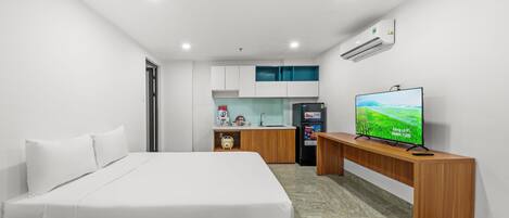 A hotel room with a bed, a TV, a small kitchenette, and a bathroom.