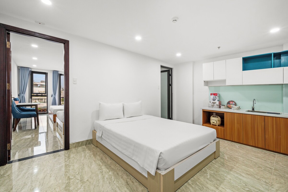 Une chambre d’hôtel moderne équipée d’un lit, d’une petite kitchenette et d’une salle de bain.