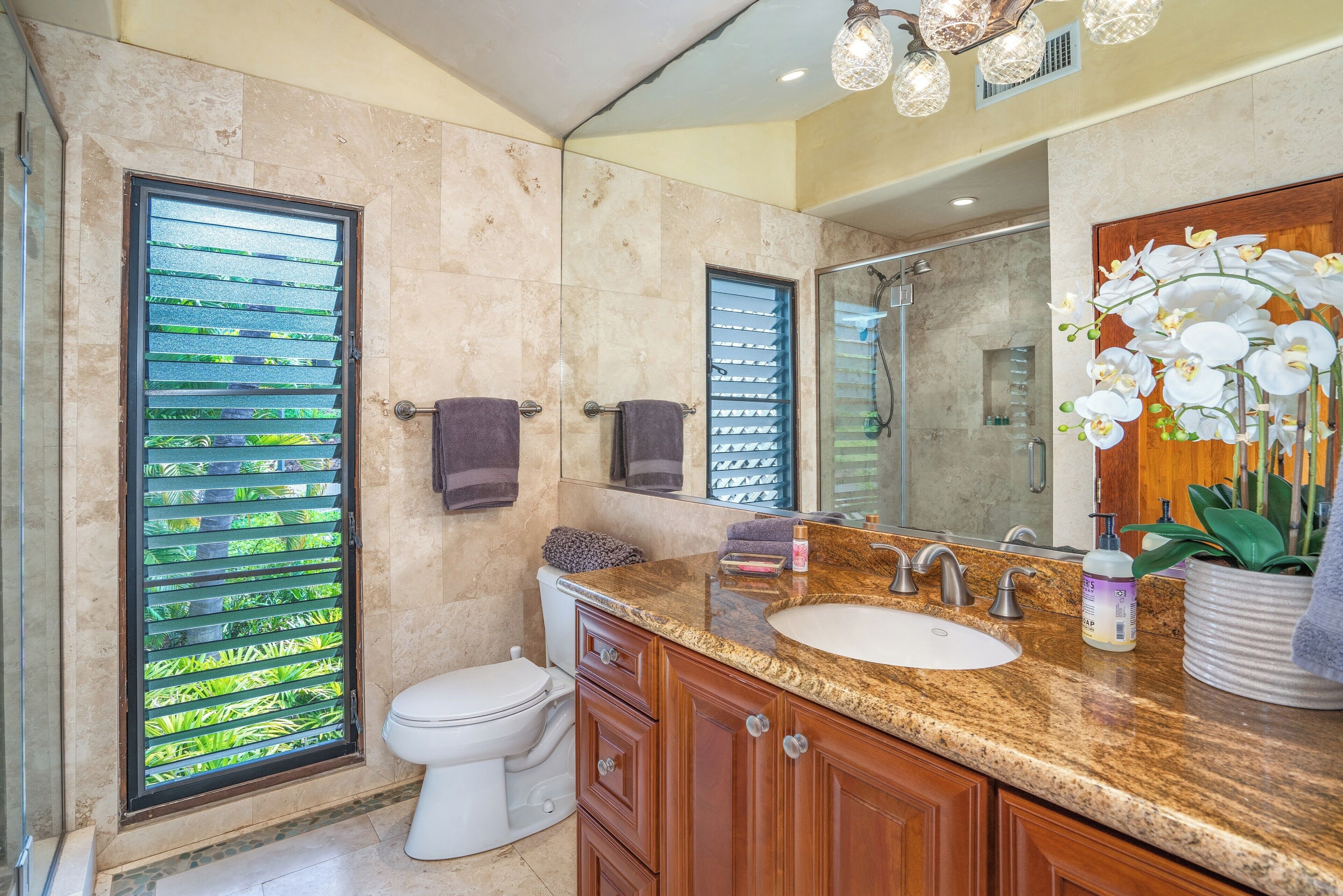 A bathroom with a marble floor, a sink with a mirror, and a toilet.