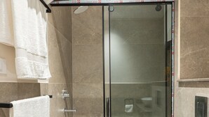 A modern bathroom with a glass-enclosed shower, a white toilet, and multiple white towels hanging on a rack. - Apartment in El Sheikh Zayed (Giza Governorate)