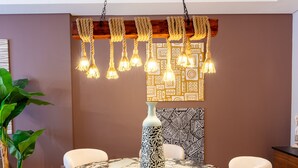 A dining area with a marble table, six upholstered chairs, a hanging light fixture, and a patterned wall decoration. - Apartment in El Sheikh Zayed (Giza Governorate)