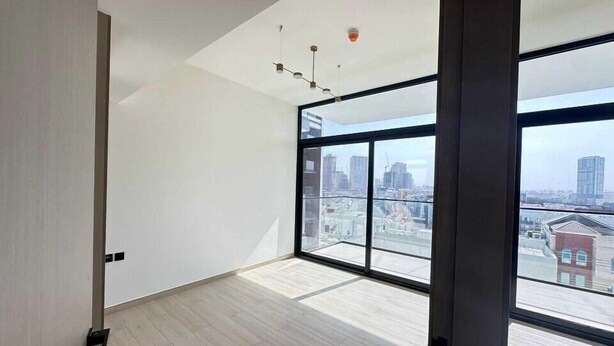A modern room with large windows, a wooden floor, and a city view.