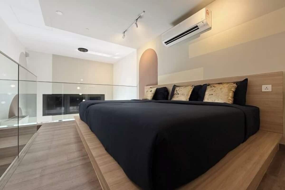 A modern bedroom with a large bed, a glass balcony, and an air conditioning unit.