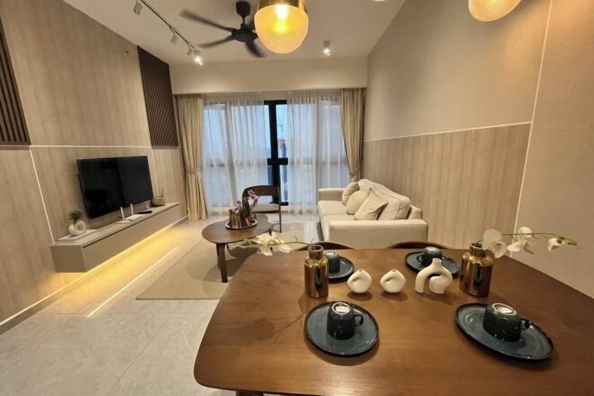 A modern living room with a flat-screen TV, a sofa, a dining table with decorative items, and a ceiling fan.