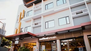 Un edificio de varios pisos con un diseño moderno, que cuenta con balcones y grandes ventanales.