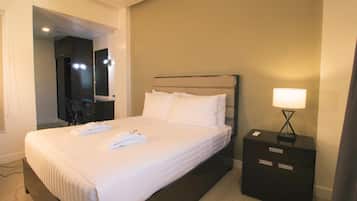 Una habitación de hotel con cama, mesita de noche, lámpara y espejo.