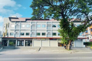 A multi-story building with various commercial establishments on the ground floor, including a coffee shop, a bakery, and a health supplements store.