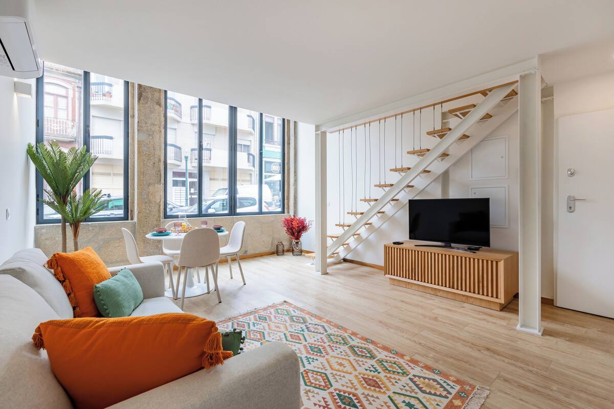 Ein modernes Wohnzimmer mit einer Couch, einem Fernseher und einer Treppe.