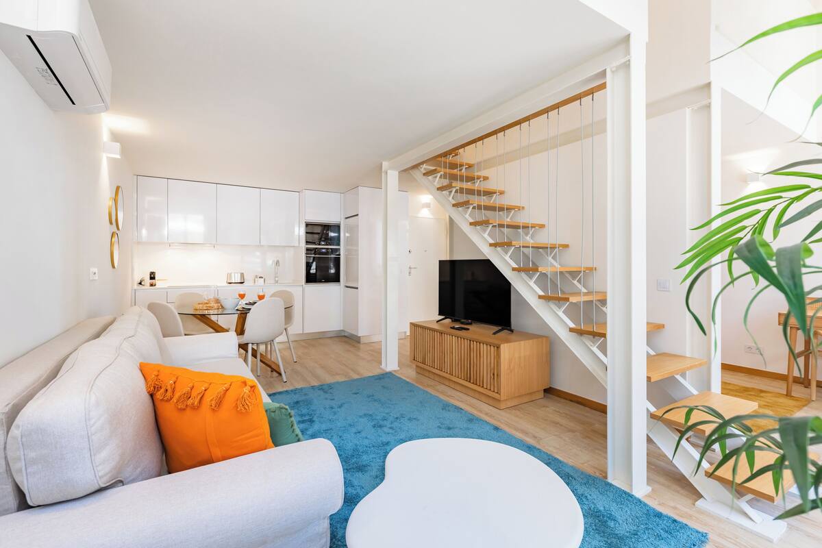 Eine moderne Wohnung mit Wohnzimmer, Küche und einer Treppe.