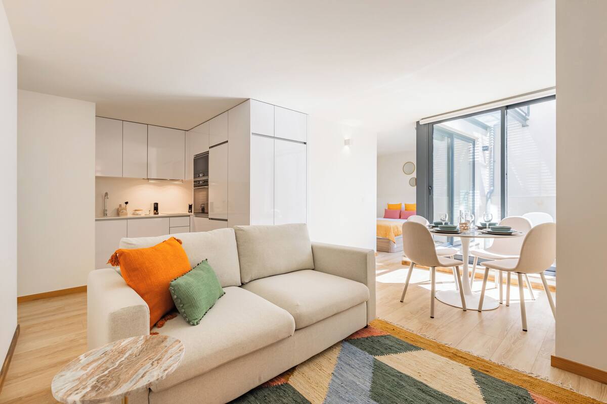 Eine moderne Wohnung mit Wohnbereich, Küche, Essbereich und einem Balkon mit Blick auf die Stadt.