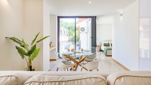A modern living room with a glass dining table, white sofas, and a potted plant. - Duque de Saldanha Residences (Porto)