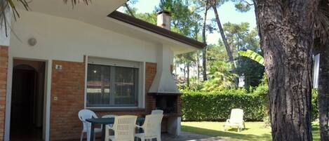 A house with a patio, a brick fireplace, and a dining area with chairs.