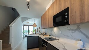 A modern kitchen with a built-in microwave, a marble countertop, and a stainless steel sink.