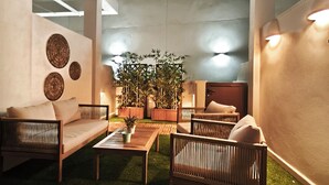 A modern outdoor living area with a sofa, chairs, a coffee table, and potted plants.