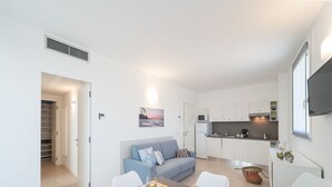 Um apartamento moderno com área de jantar, cozinha compacta e sala de estar com sofá.