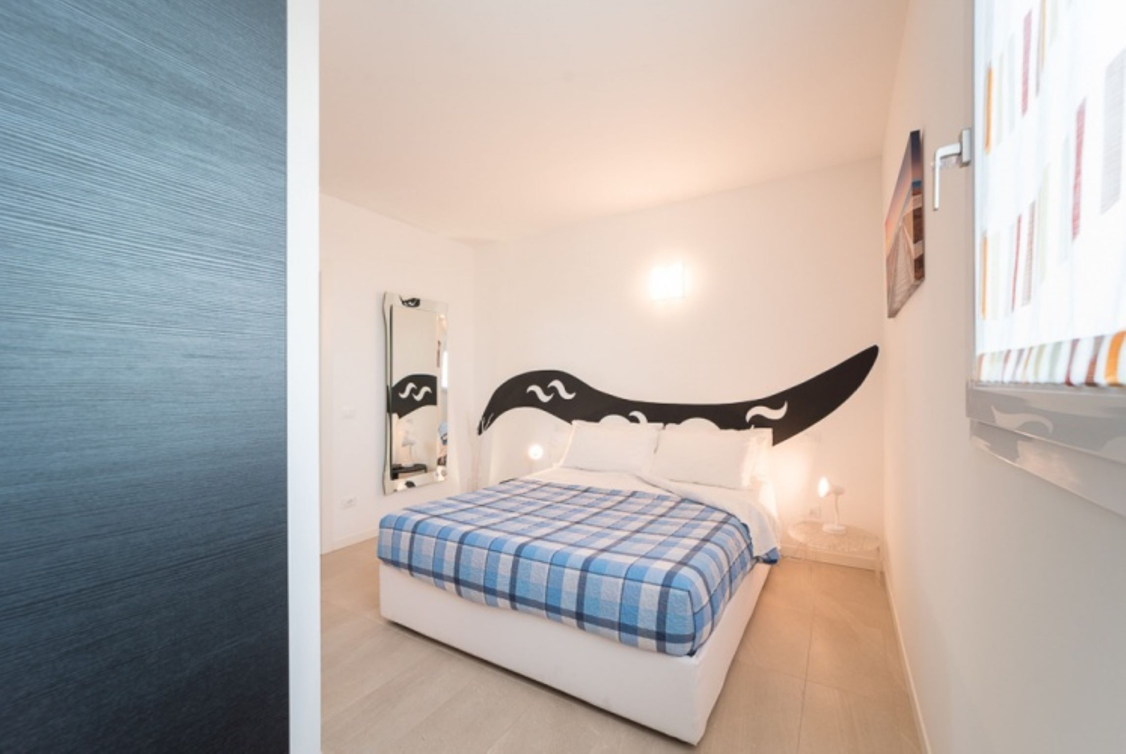 Un dormitorio con una cama, un espejo y una obra de arte colgada en la pared.
