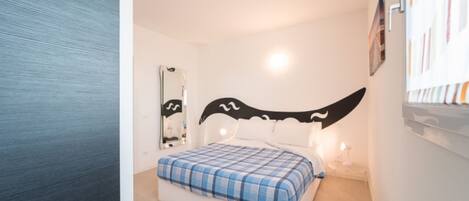 Un dormitorio con una cama, un espejo y una obra de arte colgada en la pared.