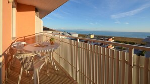 Un balcon avec une table et des chaises, offrant une vue sur la côte.