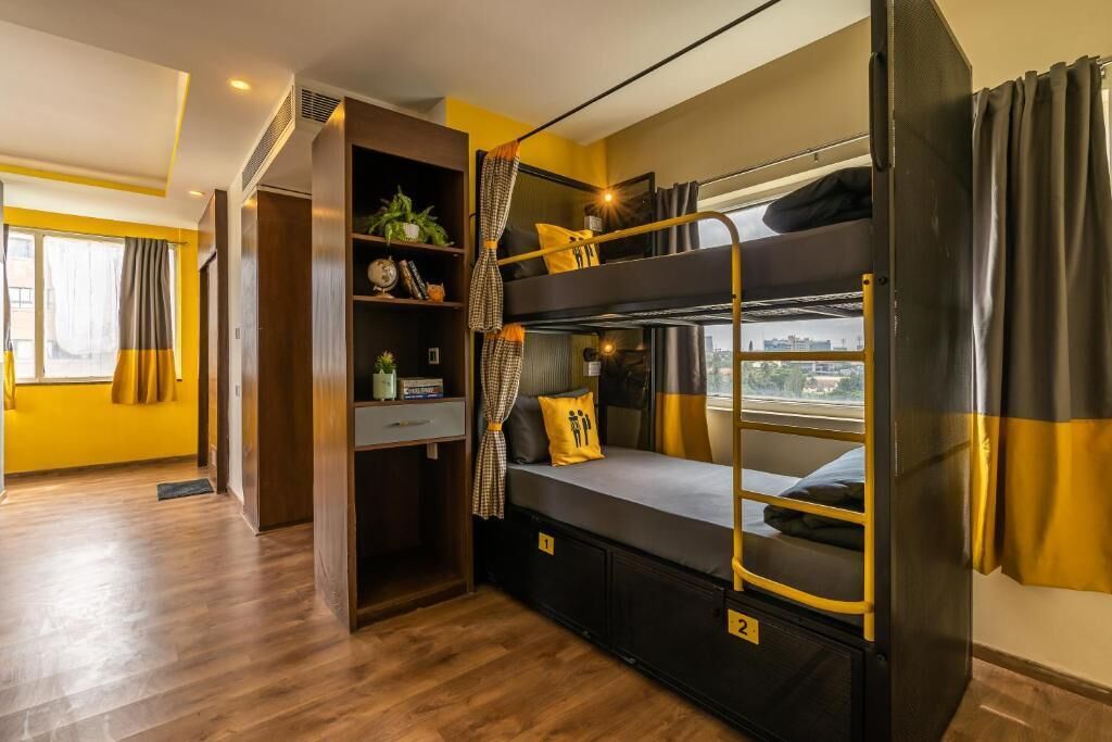 A bunk bed room with a view, a small desk, and a shelf with plants and books.