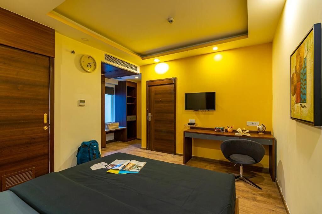 Ein Hotelzimmer mit Bett, Schreibtisch, Stuhl und Fernseher.