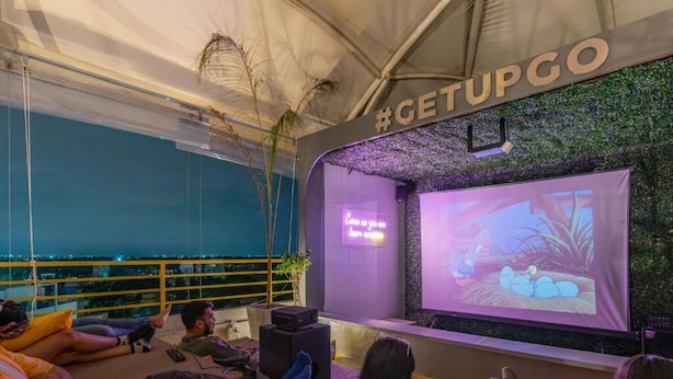 Un espace événementiel intérieur équipé d’un écran de projection, de zones d’assise et d’un panneau indiquant un mot-dièse.
