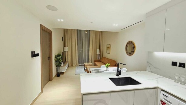 A modern kitchen with a white countertop, a sink, and a built-in dishwasher. - OYO HOME 1404 Premium 1bed Apt At Jvc Be (Dubai)