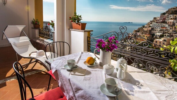 A balcony with a table set for tea, overlooking a coastal town. - My Rental Homes - Casa Li Galli  5mins' walk from Positano center, terrace, sea view (Positano)