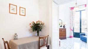 A dining area with a table, chairs, a vase of flowers, and framed pictures on the wall. - My Rental Homes - Casa Li Galli  5mins' walk from Positano center, terrace, sea view (Positano)