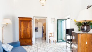 A living room with a blue sofa, wooden cabinet, and a tiled floor. - My Rental Homes - Casa Li Galli  5mins' walk from Positano center, terrace, sea view (Positano)