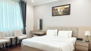 A hotel room with a large bed, a bedside table, a chair, a desk, a lamp, and a painting on the wall. - A25 Hotel - Hoang Dao Thuy 2 (Hanoi)
