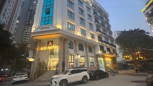 A multi-story hotel with a prominent entrance and a white SUV parked in front. - A25 Hotel - Hoang Dao Thuy 2 (Hanoi)