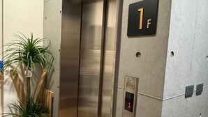 Un ascenseur avec une finition métallique, un écran numérique et une indication du numéro de l’étage, soit le 1er étage.