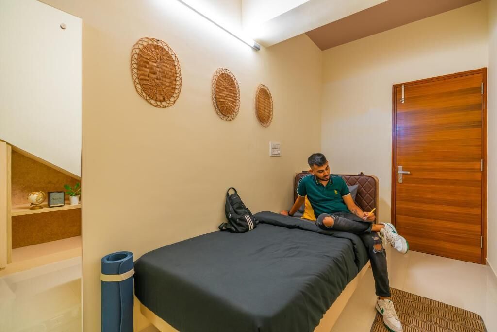 Una habitación con una cama, una puerta de madera y tres adornos tejidos en la pared.