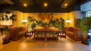 A cozy lounge area with leather sofas, a central coffee table, and potted plants.