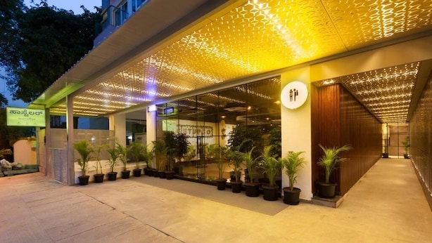 A hotel entrance with a covered walkway, potted plants, and a signboard.